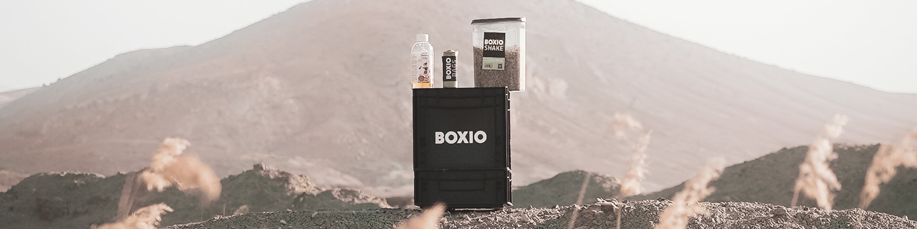 Schwarze Box mit Boxio-Produkten, im Hintergrund eine hügelige Landschaft und sanfte Hügel.